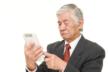 senior Japanese businessman using tablet computer looking confused