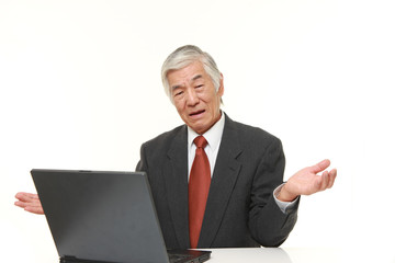 senior Japanese businessman using computer looking confused