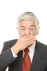 senior Japanese businessman making the speak no evil gesture