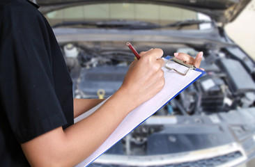 Portrait of smiling young female mechanic inspecting on a car in