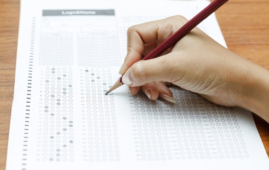 hand of women holding pencil on Standardized test form with answ