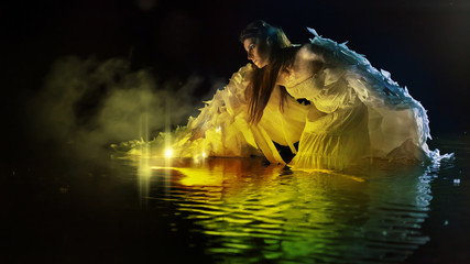Beautiful white angel is standing in the magic water.