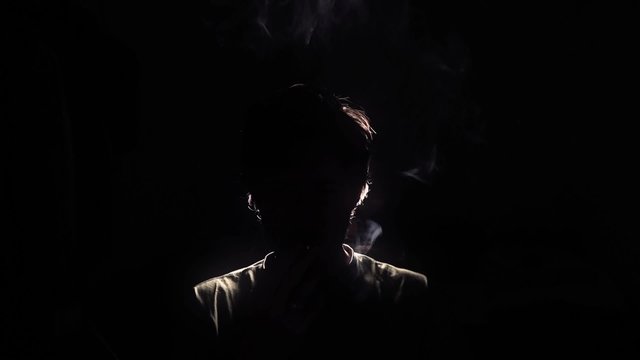 Man smoking dope silhouette back lit - 1080p. Back Lit Silhouette of man smoking in a dark room - Full HD