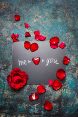 Valentines day lettering background on chalkboard with red hearts and rose petals, top view. Me plus you. Love symbols