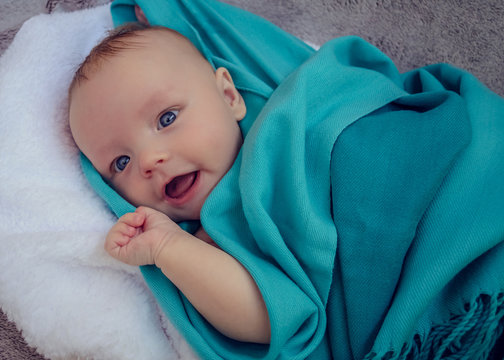 Smiling Baby Covered In Blue Blanket
