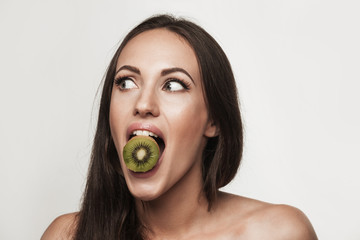 Funny portrait of young woman holding kiwifruit