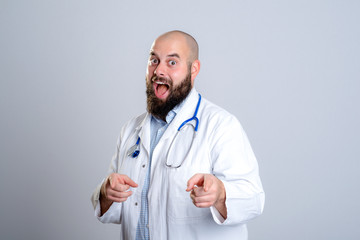 young doctor in white coat smiling and pointing in to the camera