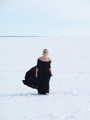 girl in a black ball gown on the lake in winter