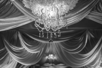 B&W wedding ceremony arches decorated with fabrics, chandeliers and bouquet.