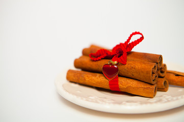Cinnamon Sticks connected by a red tape on a white background fo