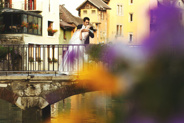 Happy romantic married couple kissing and hugging on old bridge