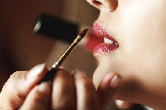 Expert stylist putting on lipstick on sexy caucasian bride close