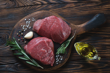 Raw filet mignon beefsteaks on a wooden chopping board, top view