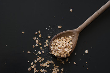 oat flakes on wooden spoon on dark wooden table