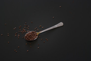 linseed on metal spoon on dark wooden table