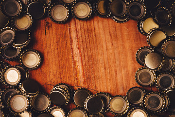 Beer bottle caps frame over wooden background