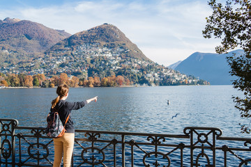 Fototapeta na wymiar Young girl looking and pointing at the panoramic scenery. Lugano