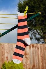 A striped sock hanging on the washing line in the garden