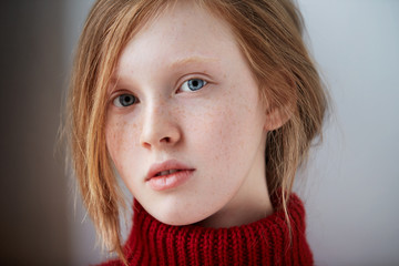 Closeup portrait of cute red haired and freckled young woman at home.