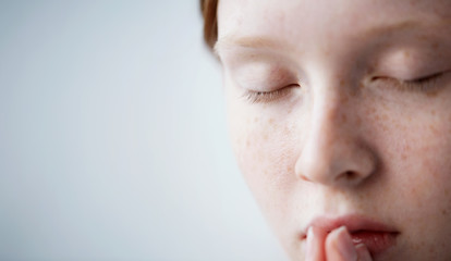 Beautiful redhead freckled young teen girl prays. Close up portrait of a female praying.
