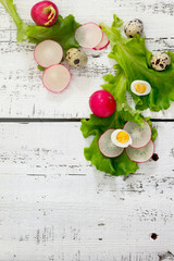 Radishes, lettuce and egg on a wooden table, top view.