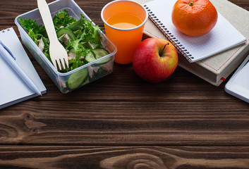 Lunch box with salad, apple, tangerine and juice.