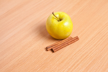 green apple and cinnamon sticks on wooden background