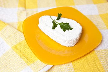 cheese on a yellow plate with a piece of parsley
