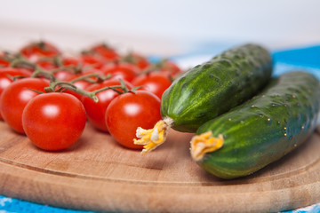 cherry tomatoes and cucumbers on a wooden background