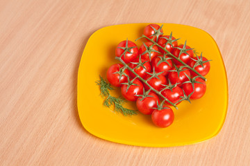 Cherry tomatoes on a branch on a yellow plate