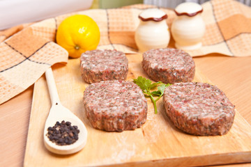 raw patties with spices on a cutting board