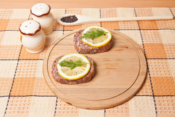 Fototapeta na wymiar raw cutlets with lemon slices on a cutting board