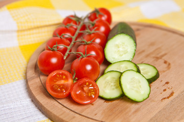 cherry tomatoes and cucumbers cut into slices on a wooden board