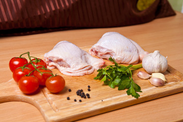 raw chicken legs with vegetables and spices on a cutting board
