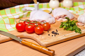 raw chicken legs with vegetables and spices on a cutting board