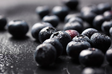 Closeup of fresh ripe blueberries on a black stone background with copy space, selective focus.