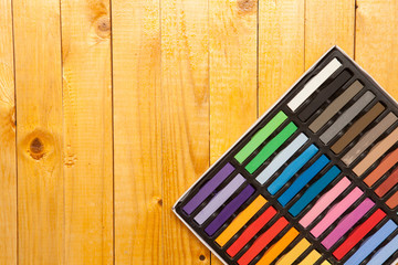 colored pastels in a box on a wooden background