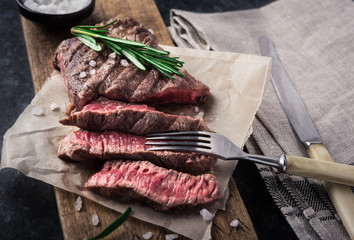 Grilled beef steak with rosemary and salt on cutting board