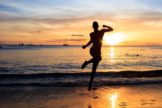 African  men jumping  at Sunset in Tarrafal beach in Santiago is