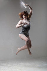 Beautiful expressive ballet dancer jumping with flour at studio