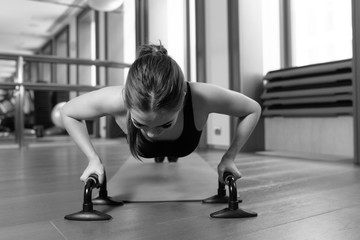 Woman doing push ups exercise. Powerful female exercising in health club.