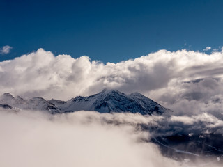 Fototapeta na wymiar Alpine mountain peak emerging from a sea of clouds- 1