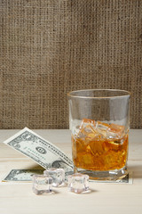 Dollars and glass of whiskey with ice