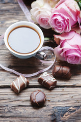 Pink roses, coffe and chocolate on the wooden table