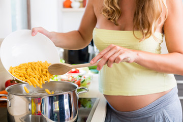 Schwangere Frau kocht Pasta in Küche zuhause