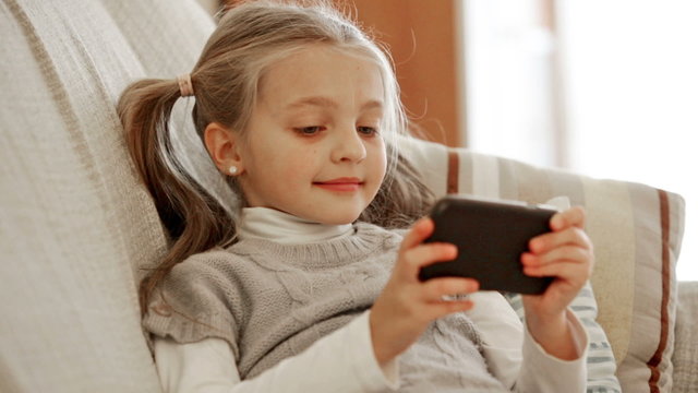 Small girl playing online and browsing web with phone