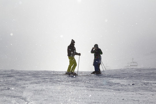 two skiers take photo on  misty  ski slope .
