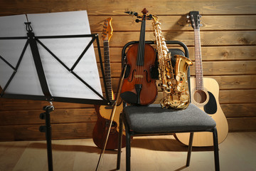 Musical instruments on a chair and note holder against wooden background