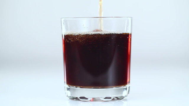 Fizzy drink is poured into a glass. White background. Close-up