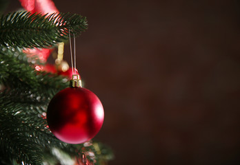 Christmas tree with decor on dark brown background, closeup